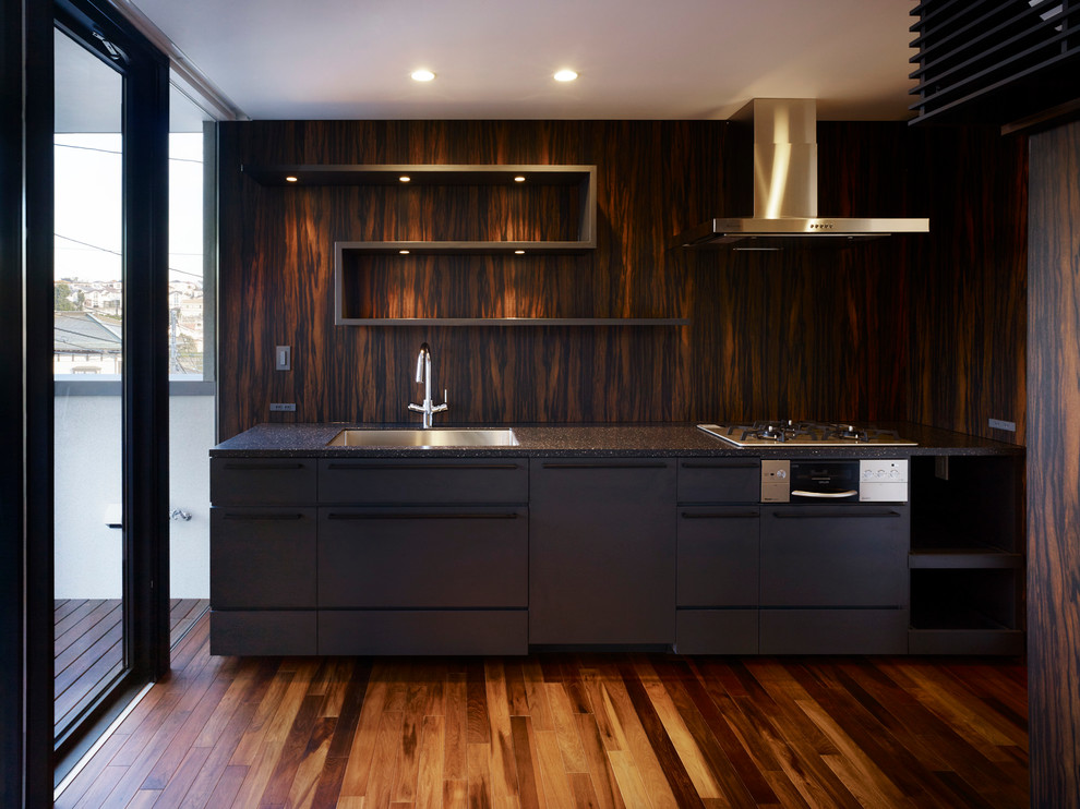 This is an example of a contemporary single-wall kitchen in Other with an undermount sink, flat-panel cabinets, black cabinets, brown splashback, stainless steel appliances, dark hardwood floors and no island.