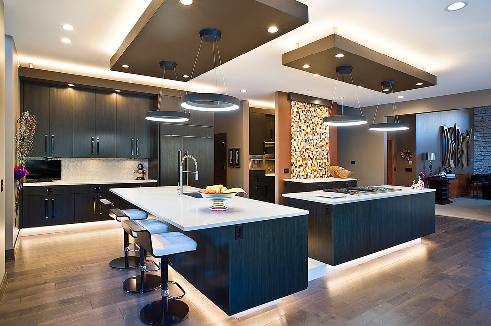 Inspiration for a large transitional l-shaped medium tone wood floor and brown floor eat-in kitchen remodel with an undermount sink, flat-panel cabinets, dark wood cabinets, quartz countertops, multicolored backsplash, mosaic tile backsplash, paneled appliances and two islands