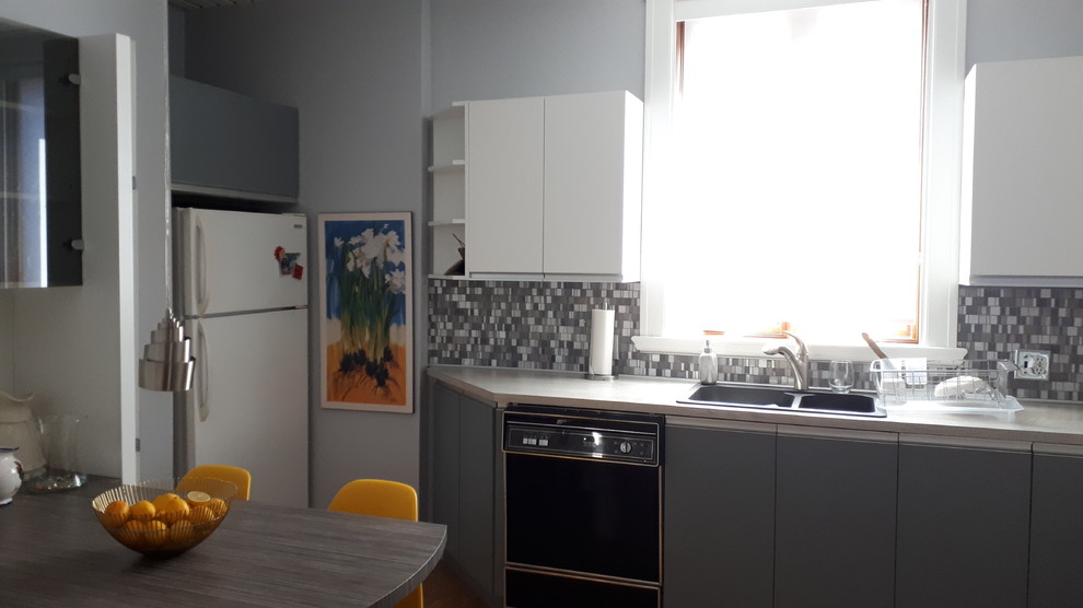 This is an example of a mid-sized contemporary u-shaped eat-in kitchen in Montreal with a double-bowl sink, flat-panel cabinets, grey cabinets, laminate benchtops, multi-coloured splashback, glass sheet splashback, white appliances, cork floors, no island, beige floor and grey benchtop.