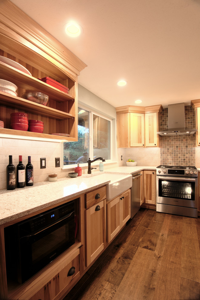 Example of a mid-sized mountain style l-shaped medium tone wood floor eat-in kitchen design in Seattle with a farmhouse sink, shaker cabinets, light wood cabinets, quartz countertops, beige backsplash, stone tile backsplash, stainless steel appliances and an island