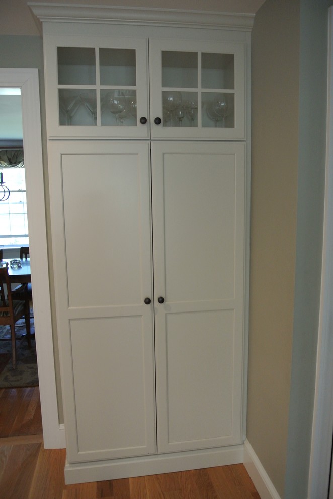Example of a transitional galley light wood floor eat-in kitchen design in Boston with an undermount sink, stainless steel appliances, an island, shaker cabinets, white cabinets, wood countertops, white backsplash, ceramic backsplash and brown countertops