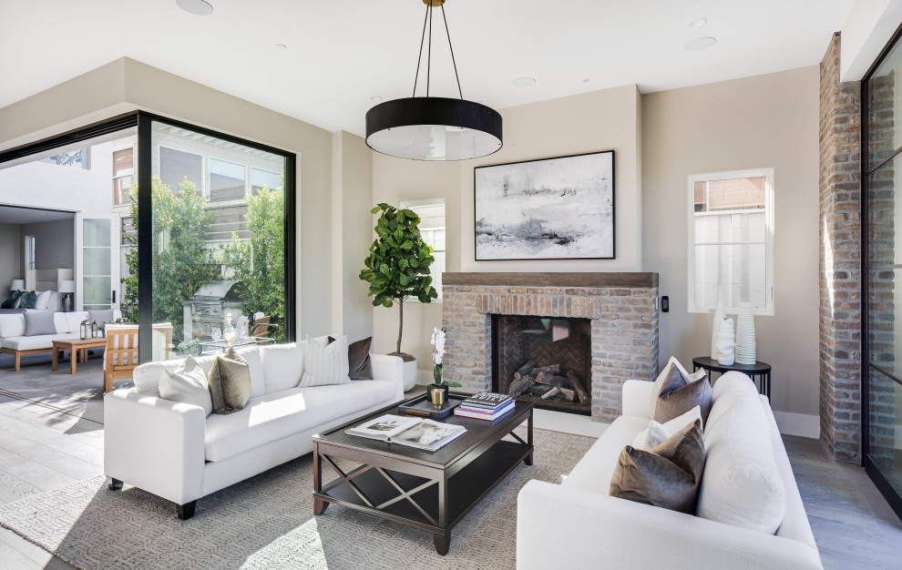 Photo of a transitional open concept living room in Orange County with beige walls, dark hardwood floors, a standard fireplace, a brick fireplace surround and brown floor.