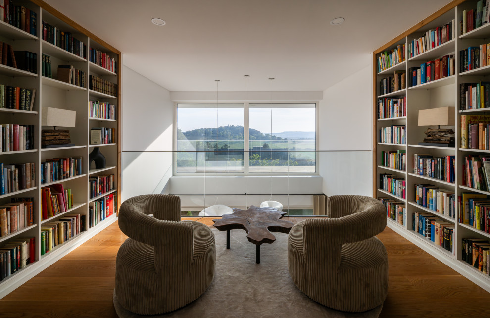 Große, Offene Moderne Bibliothek mit weißer Wandfarbe, braunem Holzboden und braunem Boden in Frankfurt am Main