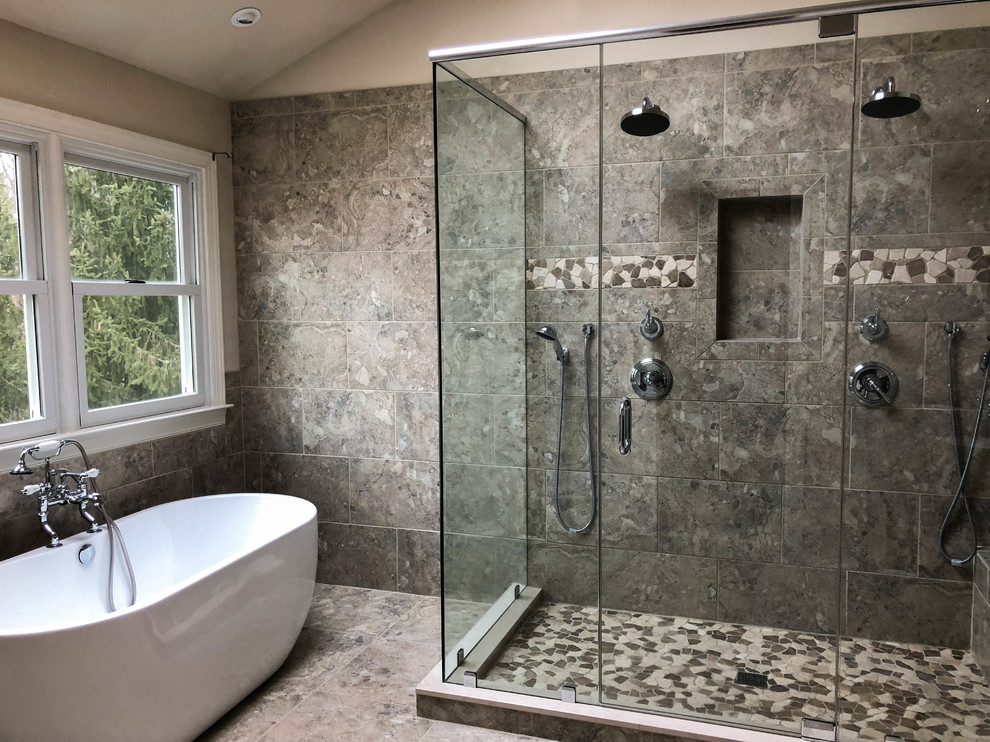Photo of a large transitional master bathroom in Philadelphia with an undermount sink, raised-panel cabinets, dark wood cabinets, granite benchtops, a freestanding tub, a corner shower, a two-piece toilet, gray tile, ceramic tile, beige walls, travertine floors and black benchtops.