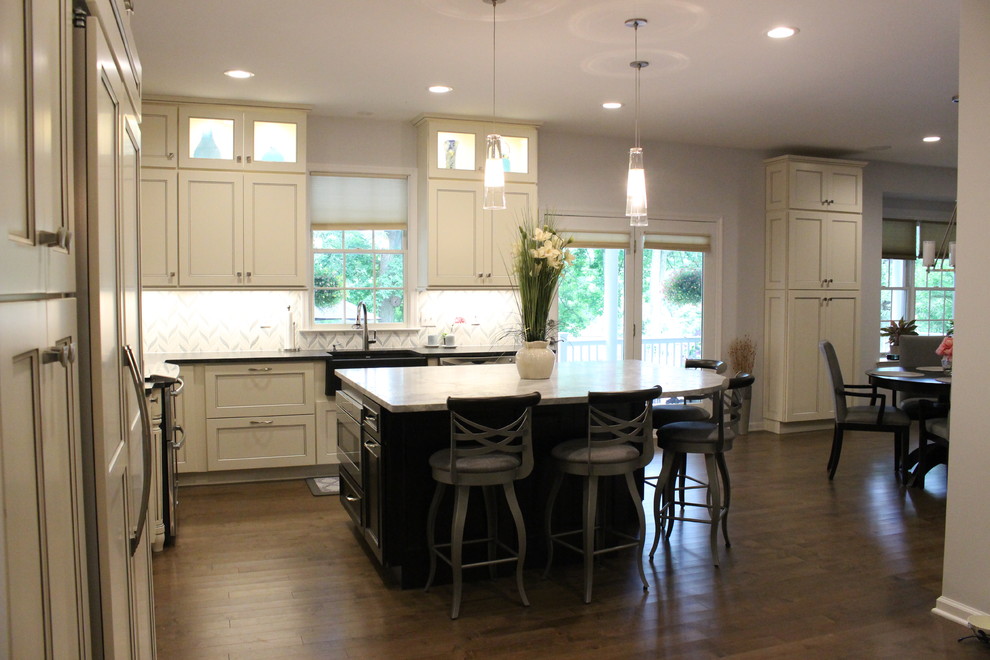 Inspiration for a mid-sized transitional l-shaped dark wood floor and brown floor eat-in kitchen remodel in New York with a farmhouse sink, recessed-panel cabinets, white cabinets, solid surface countertops, white backsplash, cement tile backsplash, stainless steel appliances and an island