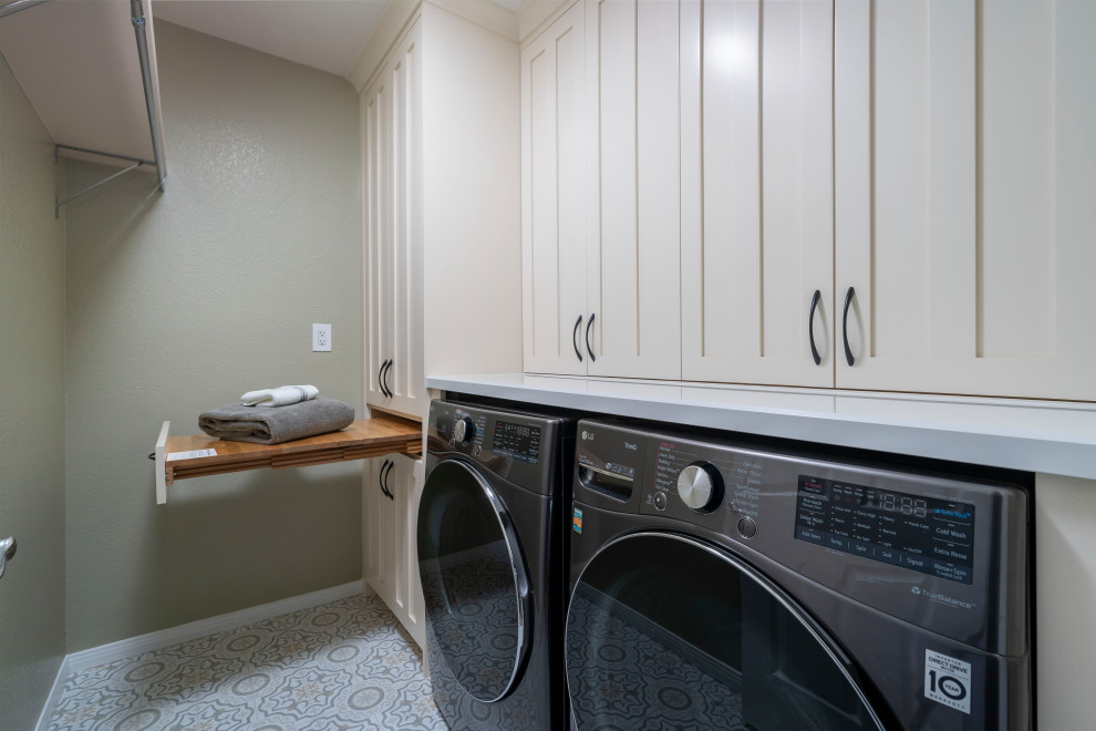 Photo of a mid-sized arts and crafts galley dedicated laundry room in Los Angeles with raised-panel cabinets, beige cabinets, quartz benchtops, green walls, porcelain floors, a side-by-side washer and dryer, beige floor and white benchtop.