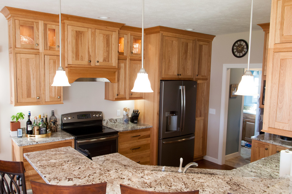Example of a mid-sized mountain style u-shaped medium tone wood floor eat-in kitchen design with an undermount sink, shaker cabinets, light wood cabinets, granite countertops, stainless steel appliances and a peninsula