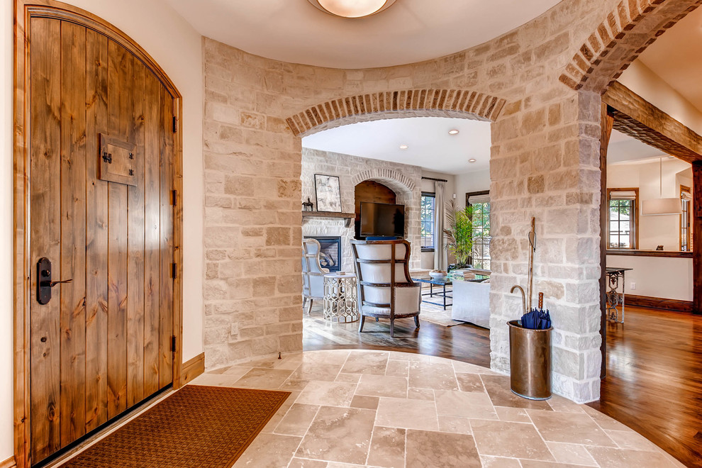 Inspiration for a large transitional vestibule in Denver with white walls, travertine floors, a single front door and a medium wood front door.