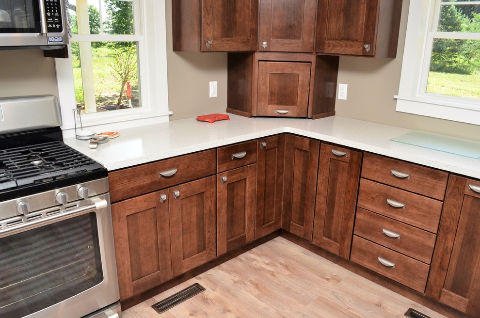 Mid-sized arts and crafts u-shaped eat-in kitchen in Other with an undermount sink, shaker cabinets, dark wood cabinets, solid surface benchtops, stainless steel appliances, a peninsula and white benchtop.