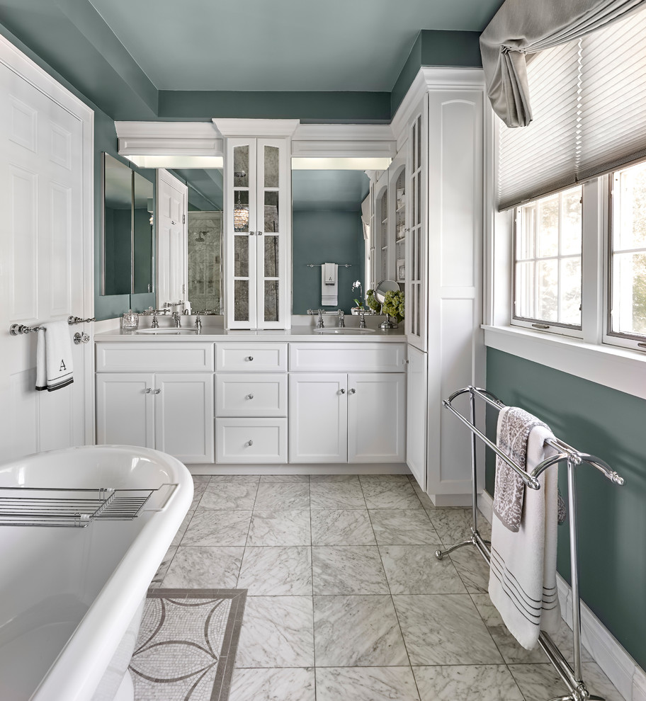 This is an example of a mid-sized transitional master bathroom in Chicago with glass-front cabinets, white cabinets, a freestanding tub, a corner shower, a two-piece toilet, blue tile, blue walls, mosaic tile floors, an undermount sink, marble benchtops, grey floor, a hinged shower door and white benchtops.