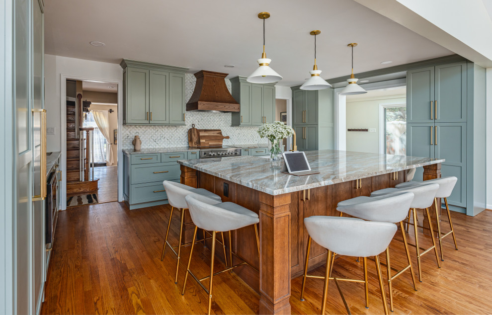 Photo of a mid-sized transitional u-shaped kitchen in DC Metro with shaker cabinets, green cabinets, grey splashback, mosaic tile splashback, stainless steel appliances, medium hardwood floors, with island, brown floor and grey benchtop.
