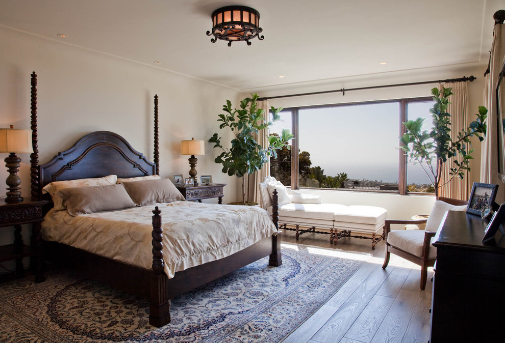 Photo of a mid-sized mediterranean master bedroom in San Diego with white walls and medium hardwood floors.