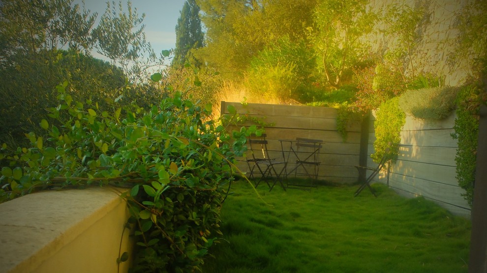 Cette image montre un jardin design avec un mur de soutènement et une terrasse en bois.