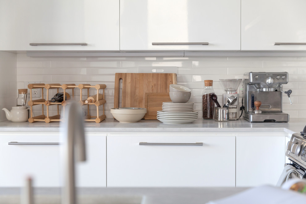 Kitchen - mid-sized modern u-shaped kitchen idea in San Francisco with white cabinets, marble countertops, white backsplash, ceramic backsplash, stainless steel appliances, no island and flat-panel cabinets