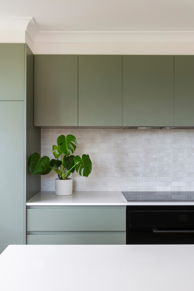 Inspiration for a medium sized contemporary l-shaped kitchen/diner in Canberra - Queanbeyan with a built-in sink, green cabinets, engineered stone countertops, white splashback, stone tiled splashback, black appliances, light hardwood flooring, an island, beige floors and white worktops.