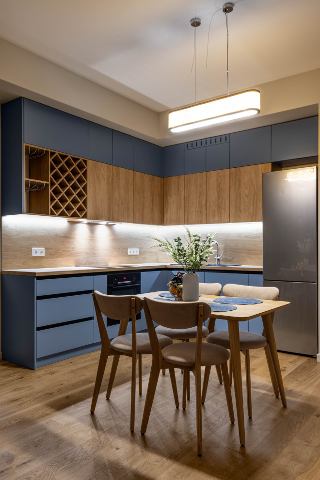 This is an example of a medium sized scandi l-shaped kitchen/diner in Saint Petersburg with a single-bowl sink, flat-panel cabinets, blue cabinets, laminate countertops, brown splashback, wood splashback, black appliances, medium hardwood flooring, no island, brown floors and brown worktops.