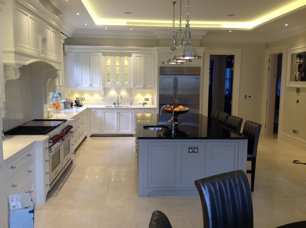 Design ideas for a large traditional l-shaped open plan kitchen in London with a double-bowl sink, shaker cabinets, white cabinets, quartzite benchtops, stainless steel appliances, travertine floors and with island.