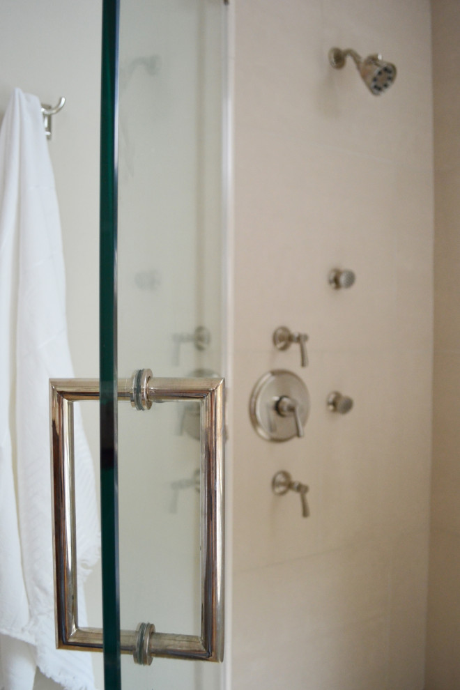 На фото: главный совмещенный санузел среднего размера в стиле неоклассика (современная классика) с фасадами в стиле шейкер, коричневыми фасадами, отдельно стоящей ванной, угловым душем, унитазом-моноблоком, бежевой плиткой, плиткой из известняка, серыми стенами, полом из известняка, врезной раковиной, столешницей из известняка, коричневым полом, душем с распашными дверями, бежевой столешницей, тумбой под две раковины, встроенной тумбой и многоуровневым потолком