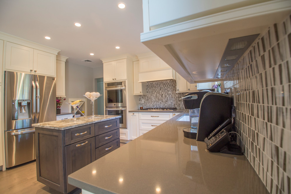 Inspiration for a mid-sized transitional l-shaped dark wood floor eat-in kitchen remodel in New York with an undermount sink, recessed-panel cabinets, beige cabinets, quartz countertops, multicolored backsplash, subway tile backsplash, stainless steel appliances and two islands