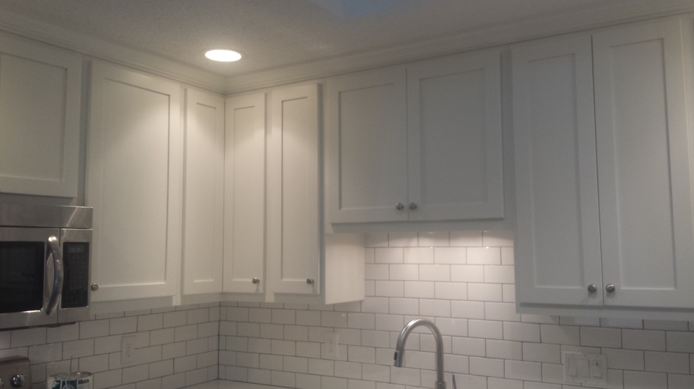 Example of an u-shaped eat-in kitchen design with an undermount sink, shaker cabinets, white cabinets, white backsplash, subway tile backsplash and stainless steel appliances