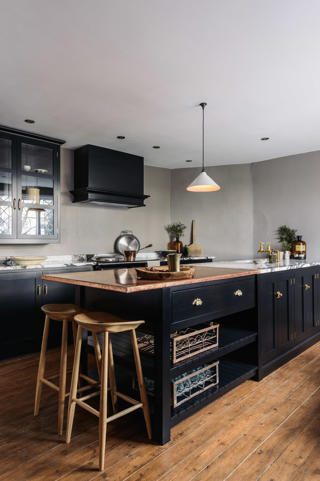 Design ideas for a mid-sized country single-wall open plan kitchen in Other with an integrated sink, shaker cabinets, black cabinets, copper benchtops, grey splashback, black appliances, medium hardwood floors and with island.