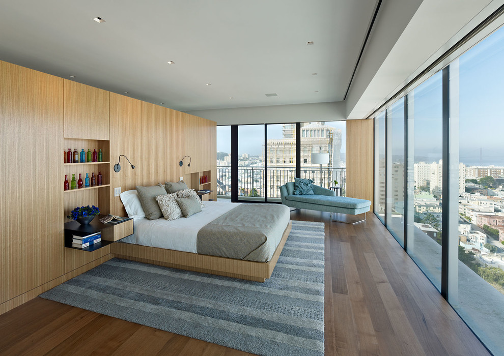 This is an example of a large modern bedroom in San Francisco with white walls and medium hardwood floors.
