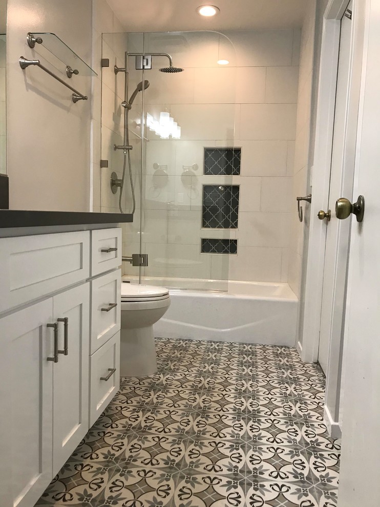 Design ideas for a mid-sized traditional master bathroom in Los Angeles with recessed-panel cabinets, white cabinets, a drop-in tub, a shower/bathtub combo, a one-piece toilet, white tile, porcelain tile, white walls, ceramic floors, an undermount sink, quartzite benchtops, a hinged shower door, multi-coloured floor, black benchtops, a niche, a single vanity and a built-in vanity.