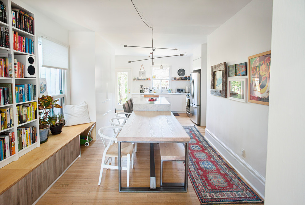 Photo of a scandinavian kitchen/dining combo in Toronto with white walls, medium hardwood floors and brown floor.