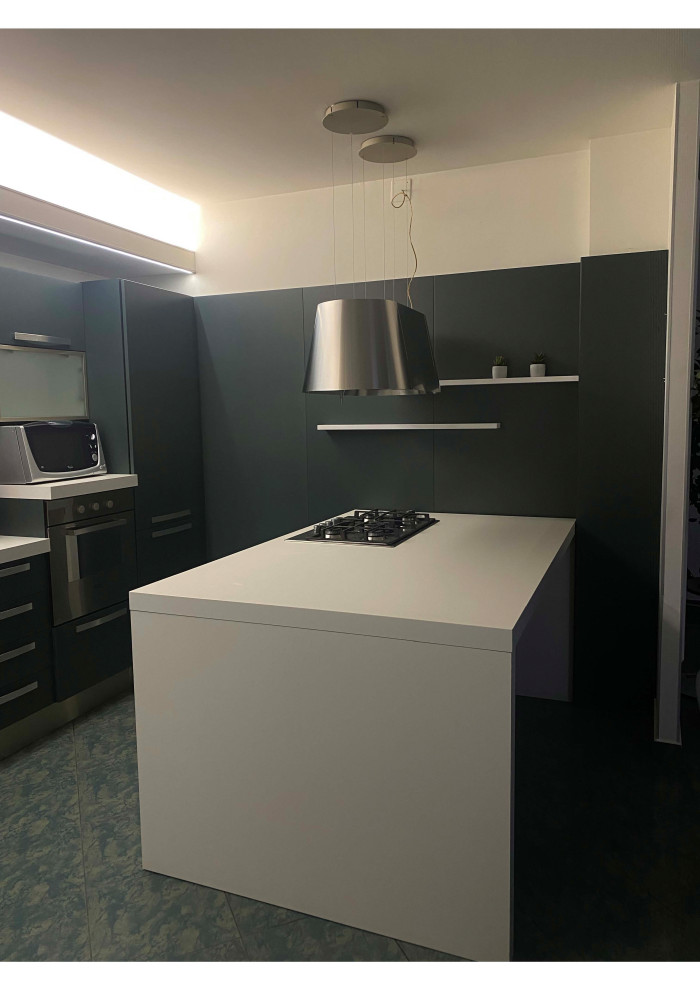 This is an example of an expansive modern eat-in kitchen in Turin with a drop-in sink, green cabinets, laminate benchtops, stainless steel appliances, ceramic floors, with island, green floor and white benchtop.