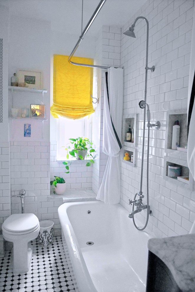 Small transitional master bathroom in New York with an undermount sink, furniture-like cabinets, black cabinets, marble benchtops, a freestanding tub, a shower/bathtub combo, a one-piece toilet, white tile, subway tile, white walls, porcelain floors and a shower curtain.