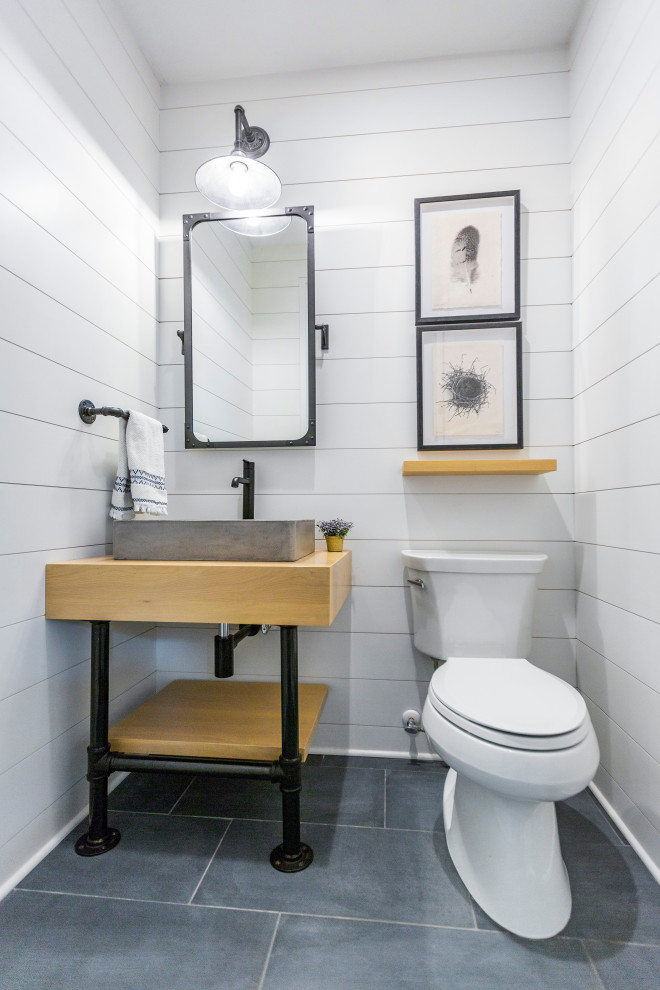Idées déco pour un WC et toilettes campagne avec WC séparés, un mur blanc, un sol en carrelage de céramique, une vasque, un plan de toilette en bois, un sol gris, du lambris de bois et meuble-lavabo sur pied.