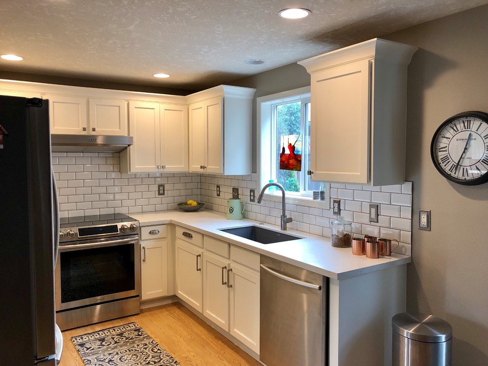 Design ideas for a small traditional u-shaped separate kitchen in Portland with an undermount sink, recessed-panel cabinets, white cabinets, quartz benchtops, subway tile splashback, stainless steel appliances, light hardwood floors, no island, yellow floor and white benchtop.