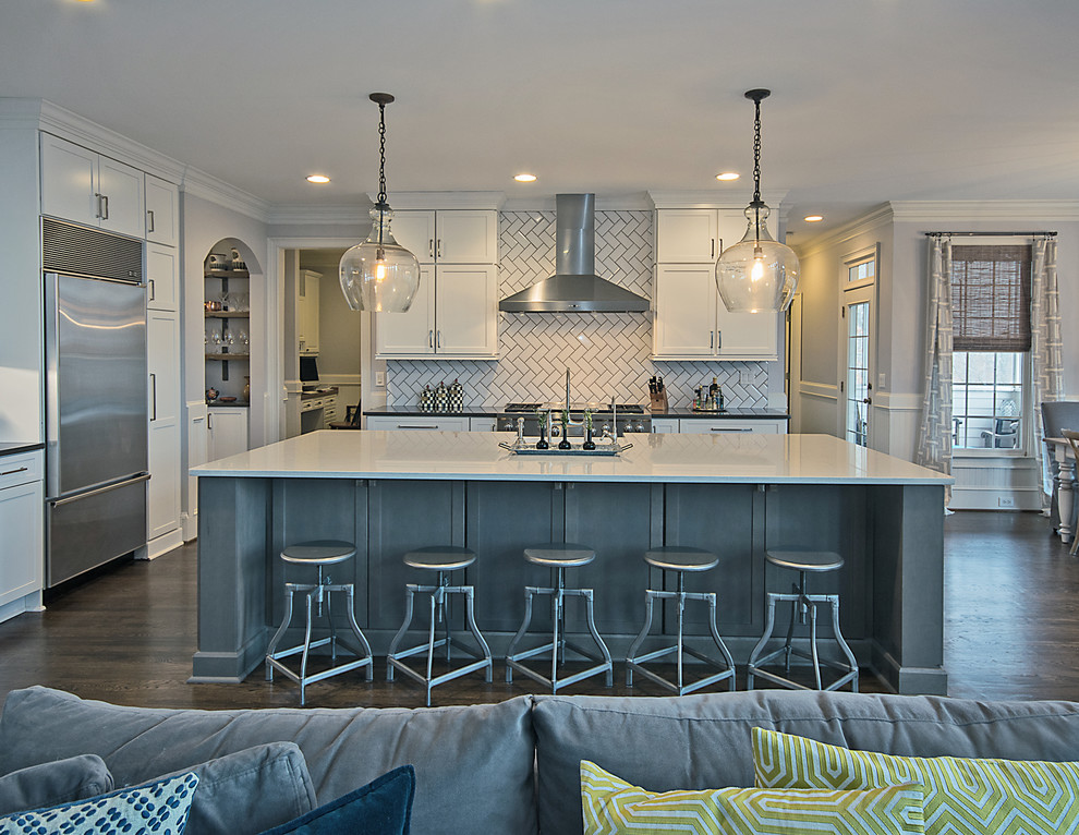 Example of a large transitional l-shaped medium tone wood floor and brown floor open concept kitchen design in Atlanta with a farmhouse sink, shaker cabinets, white cabinets, quartzite countertops, white backsplash, subway tile backsplash, stainless steel appliances and an island