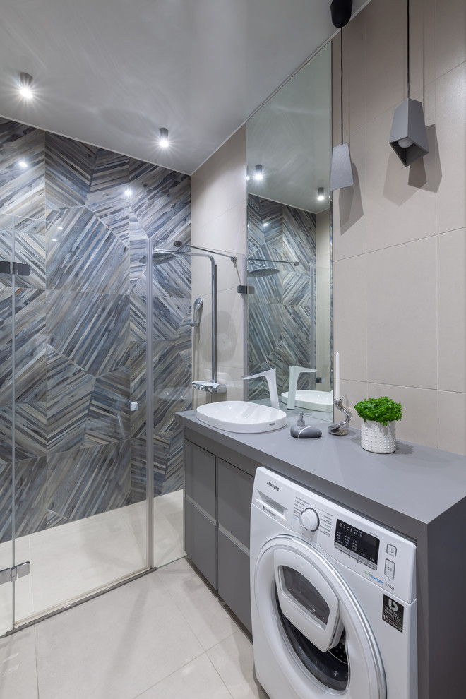 Mid-sized contemporary 3/4 bathroom in Saint Petersburg with flat-panel cabinets, grey cabinets, a wall-mount toilet, beige tile, porcelain tile, grey walls, porcelain floors, a drop-in sink, laminate benchtops, grey floor, a sliding shower screen and grey benchtops.