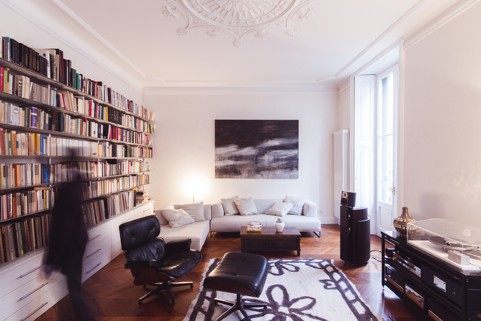 Design ideas for a contemporary living room in Milan with a library, white walls and light hardwood floors.