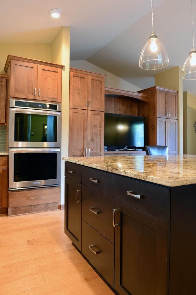Inspiration for a mid-sized transitional u-shaped light wood floor open concept kitchen remodel with an undermount sink, shaker cabinets, medium tone wood cabinets, granite countertops, glass tile backsplash, stainless steel appliances and an island