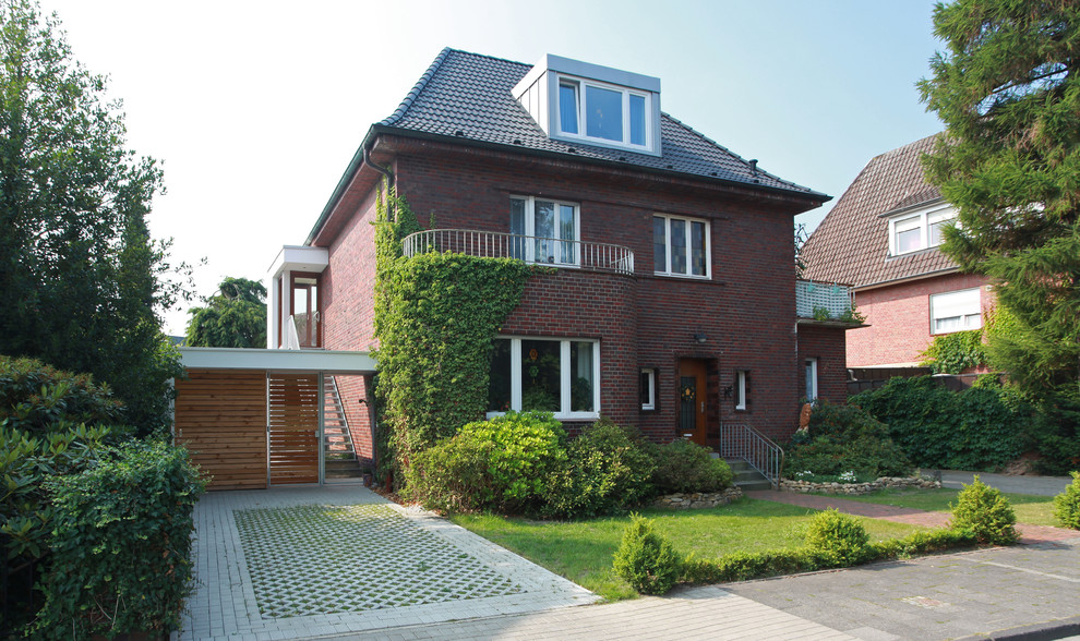 Large traditional three-storey brick brown house exterior in Other with a tile roof.
