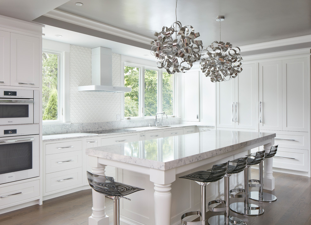 Transitional l-shaped kitchen in Boston with an undermount sink, shaker cabinets, white cabinets, white splashback, white appliances, dark hardwood floors, with island, brown floor and white benchtop.