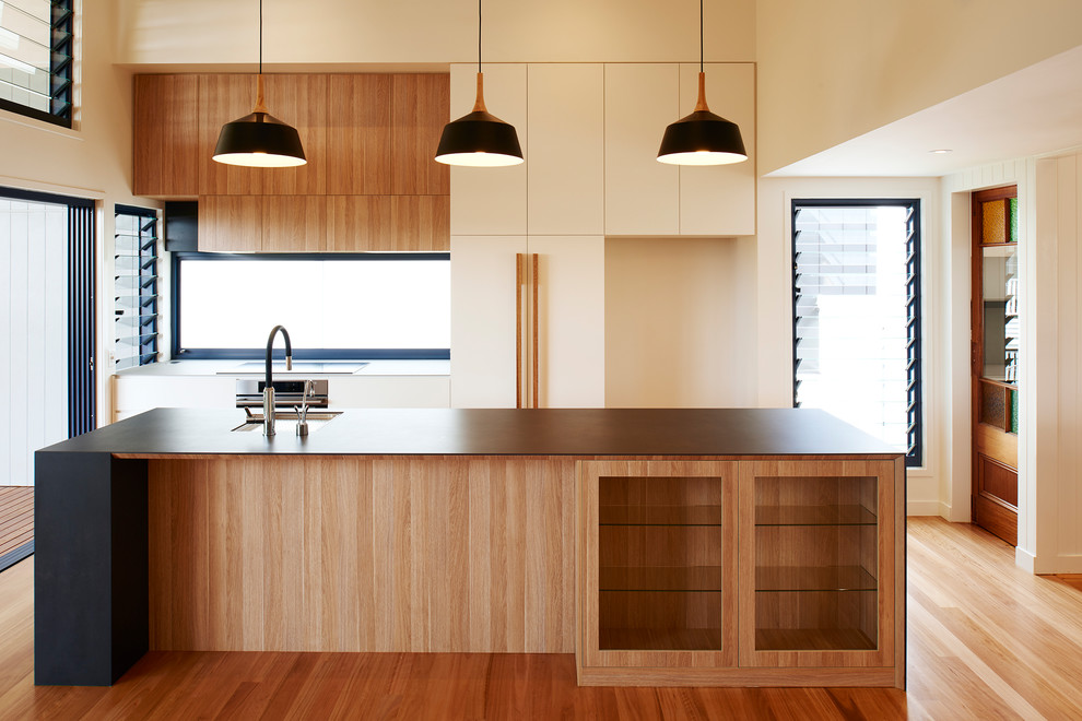 Photo of a large galley eat-in kitchen in Brisbane with an undermount sink, light wood cabinets, tile benchtops, window splashback, stainless steel appliances, light hardwood floors, with island and grey benchtop.
