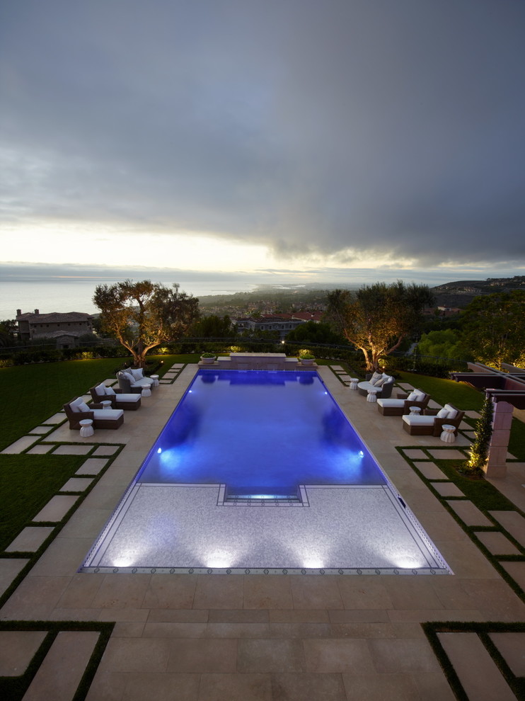 Photo of a large mediterranean backyard rectangular lap pool in Orange County with a pool house and concrete pavers.