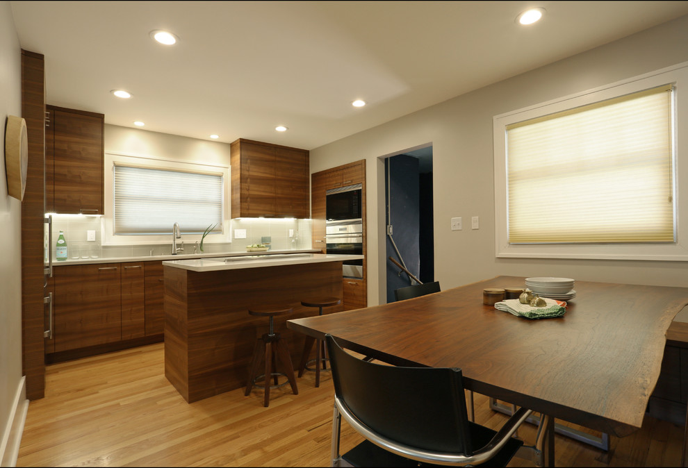 This is an example of a small contemporary u-shaped eat-in kitchen in Portland with flat-panel cabinets, dark wood cabinets, with island, quartzite benchtops, medium hardwood floors and brown floor.