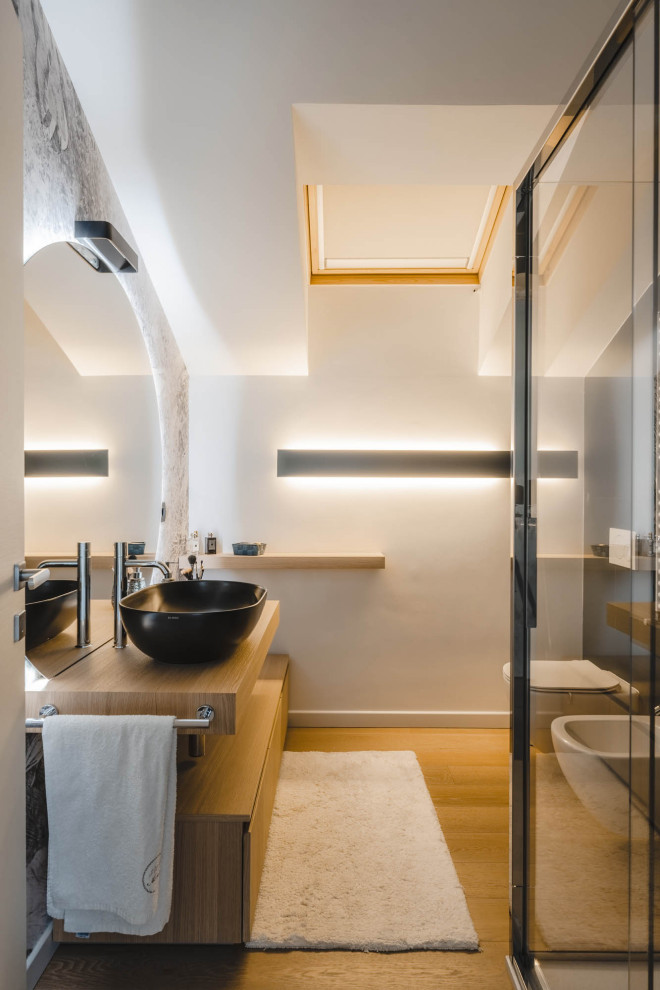 Inspiration for a small contemporary 3/4 bathroom in Milan with light wood cabinets, a curbless shower, a wall-mount toilet, white tile, porcelain tile, multi-coloured walls, light hardwood floors, a vessel sink, wood benchtops, beige floor, a sliding shower screen, beige benchtops, a single vanity, a floating vanity and wallpaper.