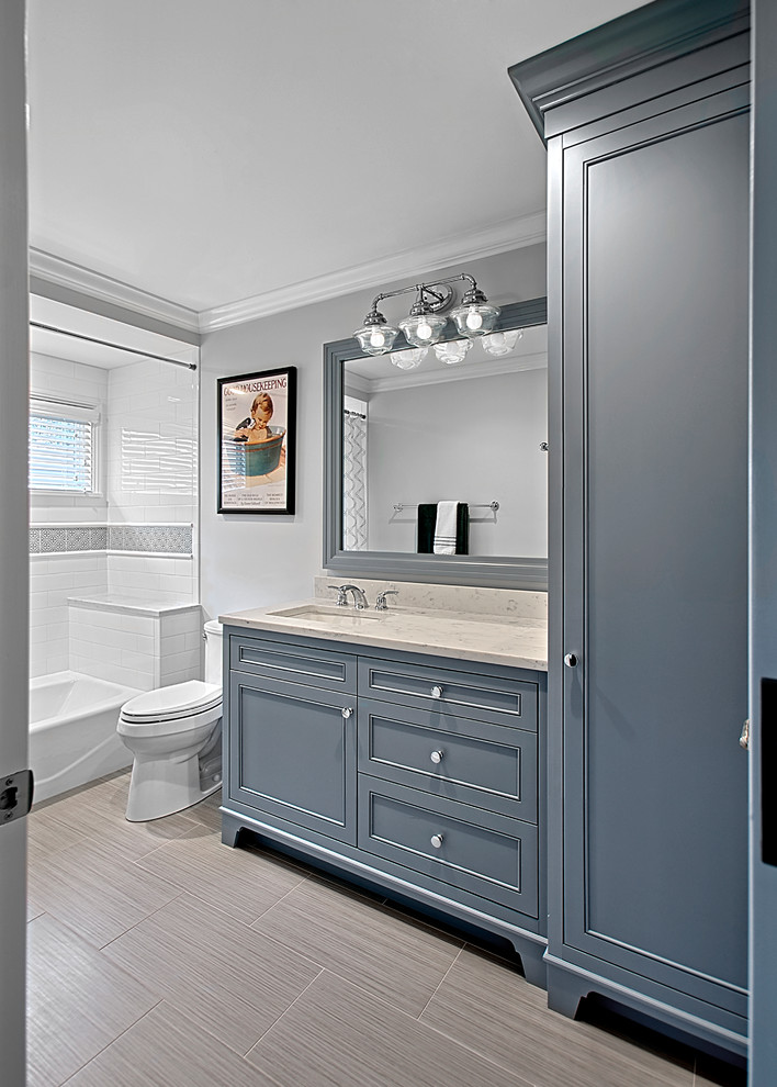 This is an example of a mid-sized transitional 3/4 bathroom in Chicago with recessed-panel cabinets, grey cabinets, a corner tub, porcelain floors, a drop-in sink, grey floor, a two-piece toilet, grey walls, engineered quartz benchtops, beige benchtops, a single vanity and a built-in vanity.