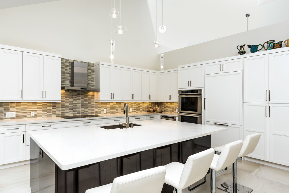 Example of a transitional l-shaped beige floor kitchen design in Miami with an undermount sink, recessed-panel cabinets, white cabinets, multicolored backsplash, matchstick tile backsplash, paneled appliances and an island