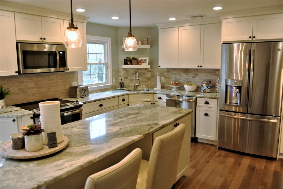 Transitional l-shaped medium tone wood floor kitchen photo in Boston with an undermount sink, shaker cabinets, white cabinets, granite countertops, beige backsplash, subway tile backsplash, stainless steel appliances and an island