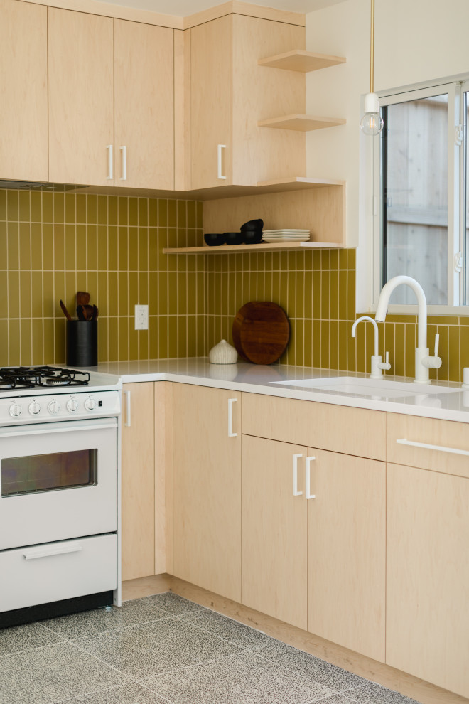 This is an example of a small scandinavian l-shaped kitchen in Los Angeles with yellow splashback, ceramic splashback, white appliances, concrete floors, no island, white benchtop, an undermount sink, flat-panel cabinets, light wood cabinets and grey floor.