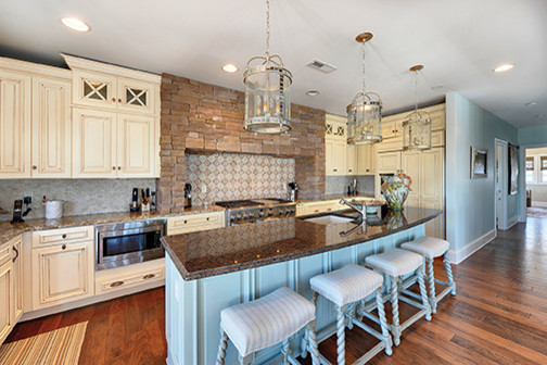 Large mountain style l-shaped open concept kitchen photo in Louisville with raised-panel cabinets, beige cabinets, granite countertops, beige backsplash, ceramic backsplash and an island