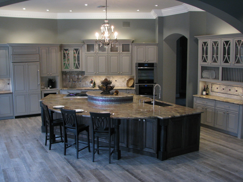 Example of a huge transitional l-shaped porcelain tile open concept kitchen design in Phoenix with an undermount sink, raised-panel cabinets, gray cabinets, granite countertops, gray backsplash, stone tile backsplash, stainless steel appliances and an island