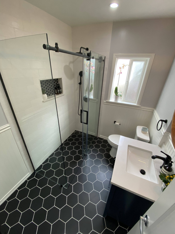 This is an example of a medium sized midcentury shower room bathroom in Los Angeles with shaker cabinets, blue cabinets, a built-in shower, a two-piece toilet, white tiles, ceramic tiles, white walls, ceramic flooring, a submerged sink, marble worktops, black floors, a sliding door, white worktops, a wall niche, a single sink, a built in vanity unit and wainscoting.