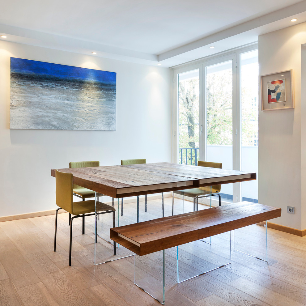 Large contemporary separate dining room in Paris with white walls, light hardwood floors and no fireplace.